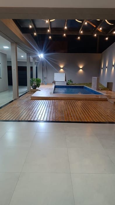O salão do Espaço Florenza à noite, iluminado, de frente para a piscina